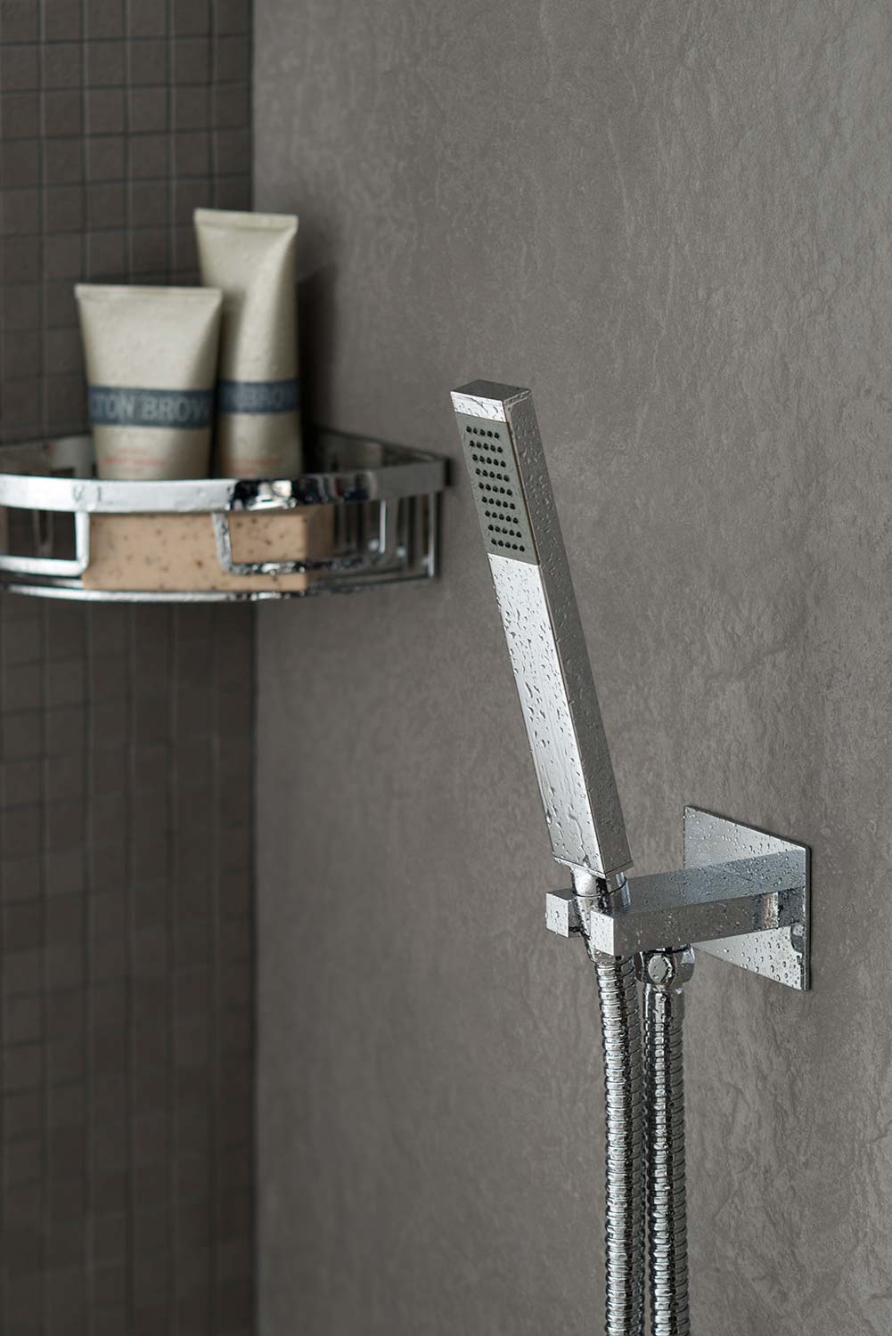 Slimline modern shower handset and wall outlet bracket on a slate wall