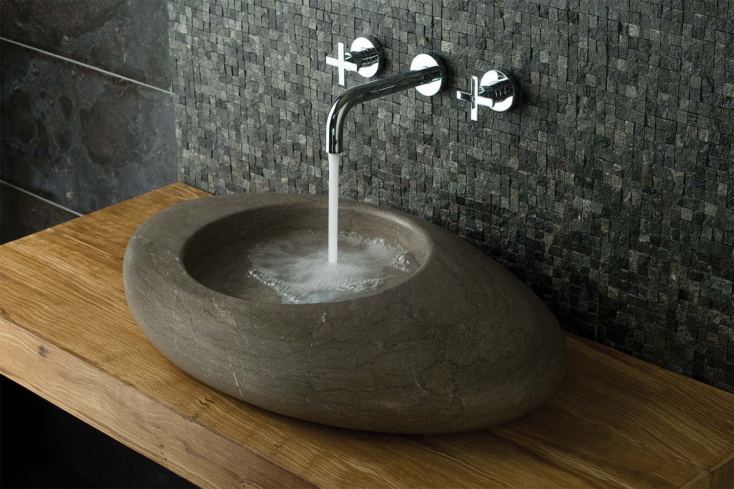3 hole wall mounted basin mixer on a grey tiled wall with water water flowing into a large stone basin on an oak shelf