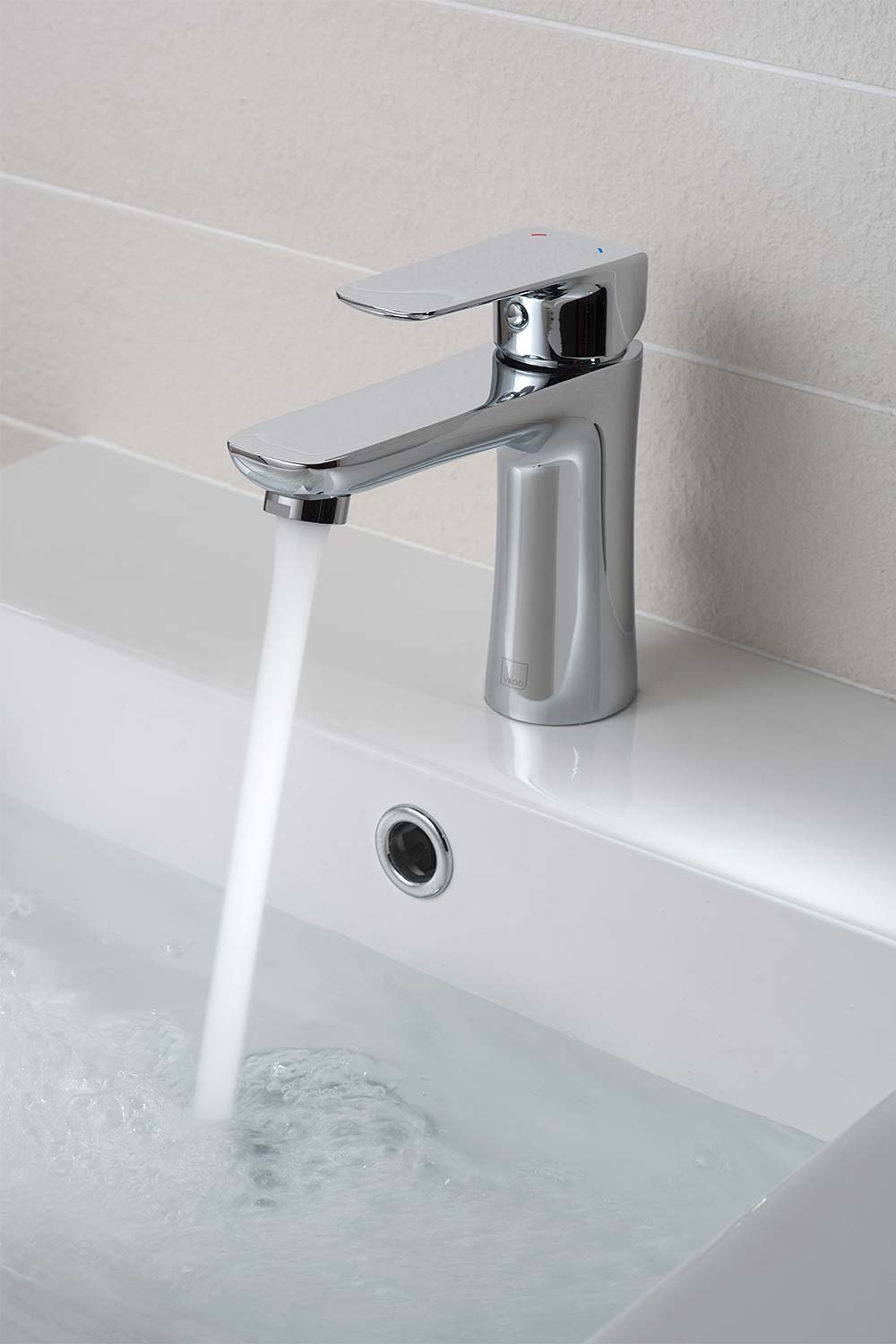 Single lever mono basin mixer with water on a white basin.