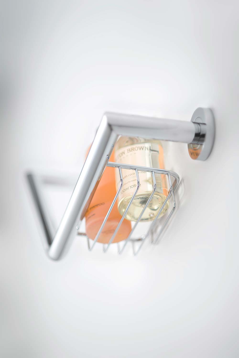 Grab rail with basket and soap bottles on a plain white background