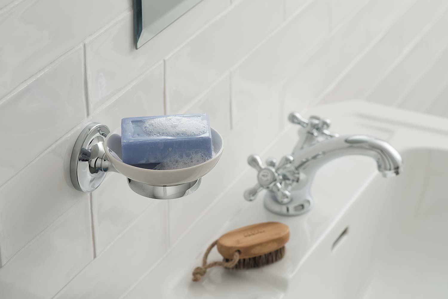 Traditional ceramic soap dish with a blue soap and chrome holder above a basin and nail brush.