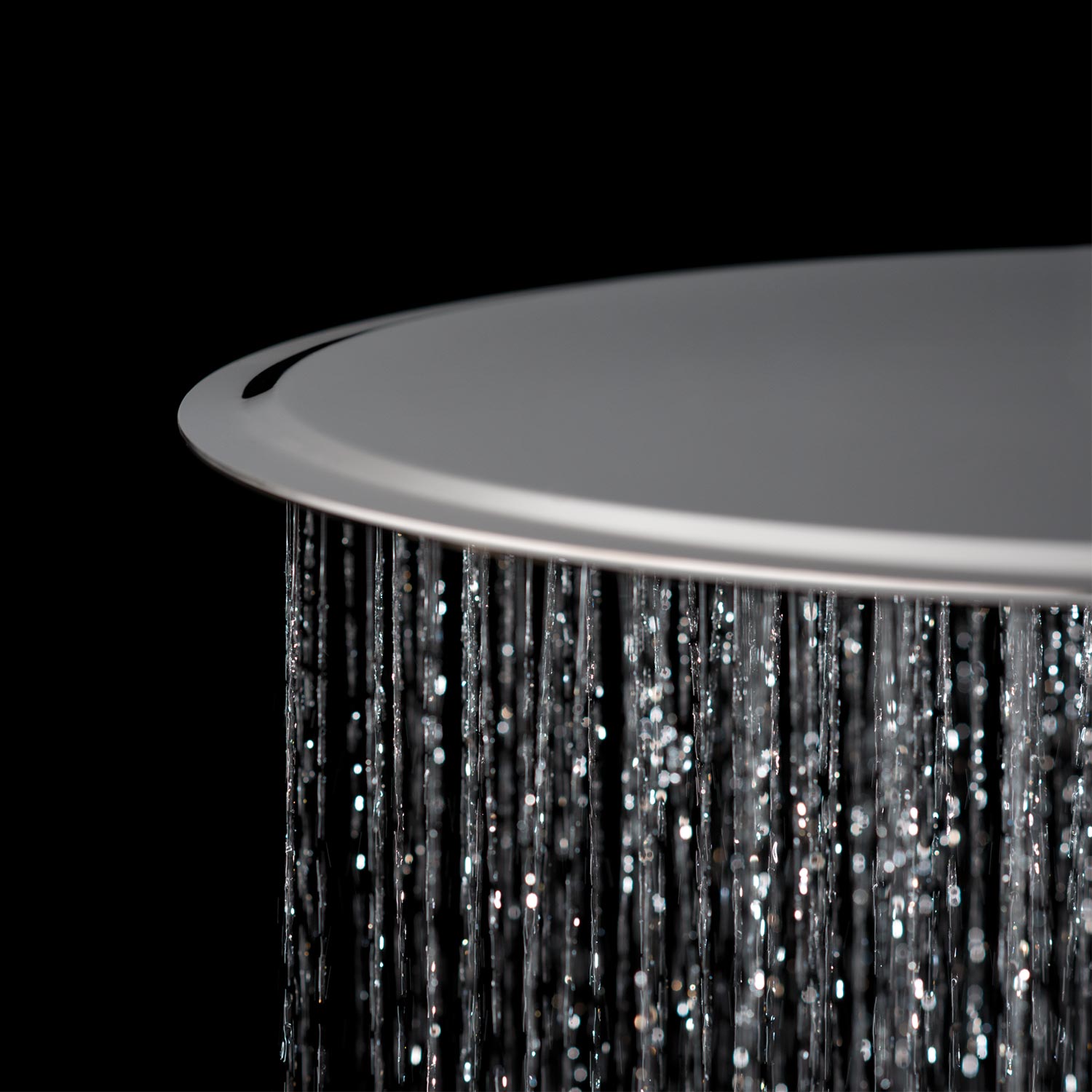 Slimline modern round shower with water cascading against a black background.