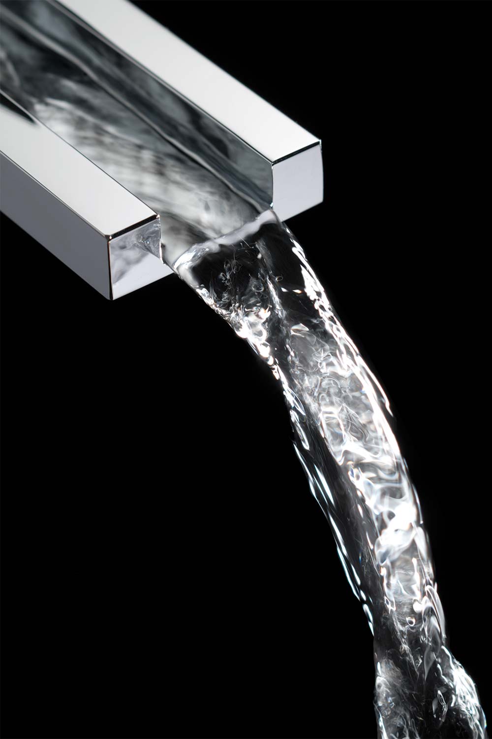 Close up of a waterfall spout with water flowing against a black background