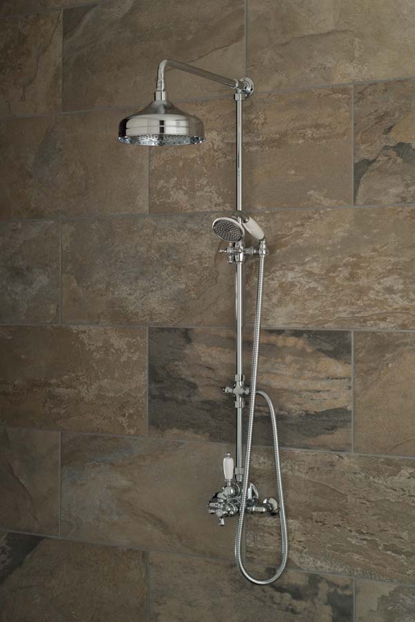 Traditional exposed shower mixer with a rigid riser, deluge shower head and handset on a brown tiled wall