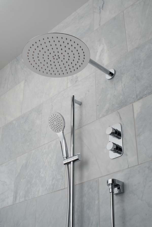 Modern round shower head and arm, wall mounted shower kit and concealed thermostatic shower valve on a marble tiled wall.