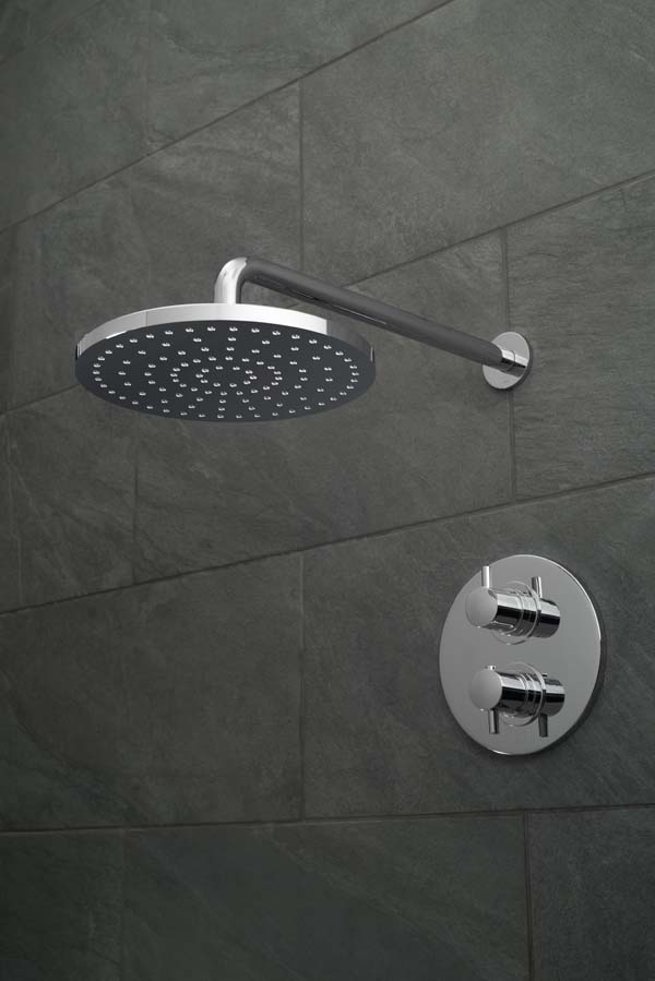 Round shower head and arm with a round concealed thermostatic shower valve on a black slate tiled wall.